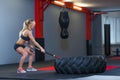 Fitness woman hitting wheel tire with hammer sledge in the gym.