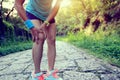 Fitness woman jogger hold her sports injured leg at forest trail Royalty Free Stock Photo