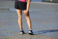 Fitness woman jogger hold her sports injured leg at seaside Royalty Free Stock Photo