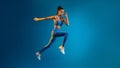 Fitness Woman Jumping In Mid-Air Over Blue Background, Panorama, Full-Length