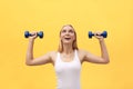 Fitness woman lifting weights smiling happy isolated on yellow background. Fit sporty Caucasian female fitness model. Royalty Free Stock Photo