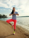 Fitness woman making yoga exercises on sand beach of river Royalty Free Stock Photo
