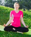 Fitness woman in pink T-shirt is sitting and meditating