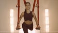 Woman practicing yoga with straps in studio. Serious lady training indoors