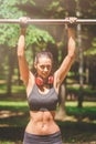 Active and young woman with headphones doing pullups Royalty Free Stock Photo