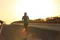 Fitness woman runner running on sunrise road