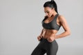 Fitness woman showing abs and flat belly, on gray background. Beautiful athletic girl, shaped abdominal