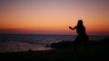 Fitness woman in silhouette doing squats exercises on beach near ocean. Young female in sportswear spending evening time Royalty Free Stock Photo