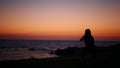 Fitness woman in silhouette doing squats exercises on beach near ocean. Young female in sportswear spending evening time Royalty Free Stock Photo