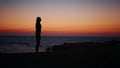 Fitness woman in silhouette doing squats exercises on beach near ocean. Young female in sportswear spending evening time Royalty Free Stock Photo