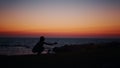 Fitness woman in silhouette doing squats exercises on beach near ocean. Young female in sportswear spending evening time Royalty Free Stock Photo