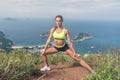 Fitness woman stretching her leg muscles doing side lunge exercise preparing for cardio work-out in mountains by the sea