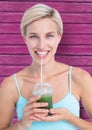 fitness woman taking a healthy juice with pink wood background