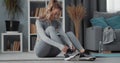 Fitness woman tying laces on sneakers at home