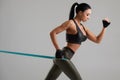 Fitness woman using a resistance band in her exercise. Sexy athletic girl workout with expander on grey background