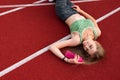 Fitness woman who lies on a running track with bottle with water in her hands. Royalty Free Stock Photo