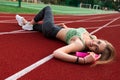 Fitness woman who lies on a running track with bottle with water in her hands. Royalty Free Stock Photo