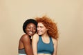 Fitness Women. Ethnic Friends Portrait. Hugging African Brunette And Caucasian Redhead Girls On Beige Background.