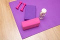 Fitness and yoga sports equipment - blocks, dumbbells, water bottle on a lavender sports mat. Place for text. Royalty Free Stock Photo