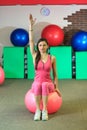 Fitness. Young beautiful white girl in a pink sports suit does physical exercises with a pink fit ball at the fitness center.