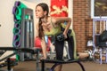 Fitness. Young beautiful white girl in a yellow and gray sports suit is doing exercises with a dumbbell on training apparatus.
