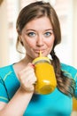 Fitness young woman drinking orange smoothie in Kitchen