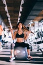 Fitness young woman with long hair in gym, sitting on Pilates ball Royalty Free Stock Photo