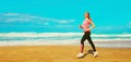 Fitness young woman running on sunny day on the beach on sea background, blank copy space for advertising text Royalty Free Stock Photo