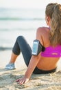 Fitness young woman sitting on beach. rear view