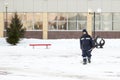 A worker assembler in winter overalls with a shovel and an iron trough walks along the con-struction site