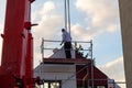 The fitter stands on a scaffold and places the component for the prefabricated house that is still on the hook and rope in its fin