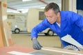 Fitter using bench saw in garage with camper vans Royalty Free Stock Photo
