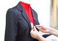 Fitting clothes on a mannequin in atelier. Tailors hands with a jacket and a pin, close up, close up, selective focus.