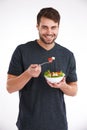 Fitting in a healthy snack. Studio portrait of a smiling young man eating salad from a bowl. Royalty Free Stock Photo