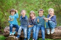 Five adorable kids, dressed in striped shirts, sitting on wooden