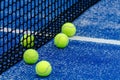 Five balls near the net of a blue artificial grass paddle tennis court. Racket sport Royalty Free Stock Photo