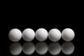 Five balls for ping pong in a row on a dark background