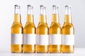 Five beer bottles with blank white labels isolated on grey.