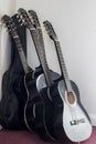 Five black classical guitars leaning against the wall. Student guitars