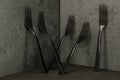 Five black plastic forks on an elegant black background