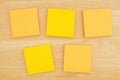 Five blank sticky notes on textured desk wood background