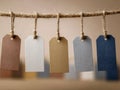 Five blank textured paper tags in neutral tones hanging on a rustic twine rope against a soft blurred background perfect for Royalty Free Stock Photo