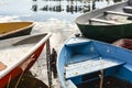 Five boats of different colors are tied with an iron, rusty chain on the bank of the river, against the background of water, in