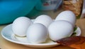 Five boiled eggs in a shell on a plate. One egg with cracks in a scarlet shell