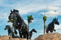Five bronze horses on rock hill at the entry to a tropical residential community