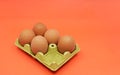 Five brown eggs instead of six in an open egg carton on orange background. Shrinkflation concept. Royalty Free Stock Photo