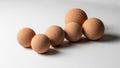 Five brown spherical objects of varying sizes are arranged on a white surface Royalty Free Stock Photo