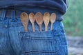 five brown wooden spoons in a blue jeans pocket