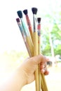Five brushes with traces of color in the hand, soft background