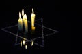 Five burning candles and the Star of David against a black background. Royalty Free Stock Photo